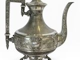une théière ancienne en argent avec une anse et une poignée, sur fond blanc