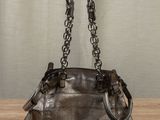 the purse is sitting on a wooden table with a curtain in the background