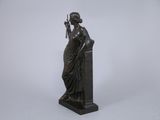a bronze statue of a woman holding a bird on a pedestal