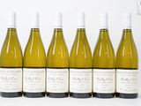 six bouteilles de vin sont alignées sur une surface blanche