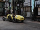 a yellow race car that is parked in a factory