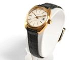 a white watch with a gold case and black band