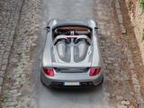 a silver sports car driving down a cobblestone road