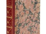 un vieux livre à la couverture rouge posé sur une surface blanche