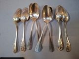 six cuillères en argent sont alignées sur une table