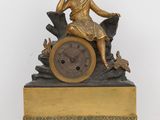 a gold clock with a woman sitting on top of it