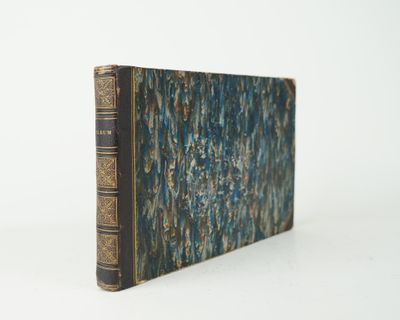 un vieux livre posé sur une table blanche à côté d'un mur blanc