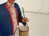 a figurine of a man with a drum and a hat