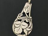 a silver pendant with a flower design on it