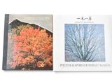 two books on a white surface with a tree in the background