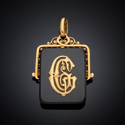 un pendentif en or et en onyxine orné de la lettre « g »