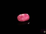 a close up of a pink stone on a black surface