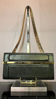 un sac à main noir posé sur une pile de valises
