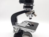 microscope noir et argenté posé sur une surface blanche, avec un fond blanc