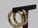 a close up of a pair of gold hoop earrings on a black stand