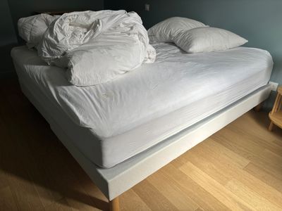 un lit recouvert de draps blancs et d'oreillers, dans une chambre