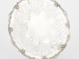 une assiette ancienne en argent, ornée d'un motif floral sur le bord