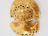 a close up of a gold figurine on a white surface
