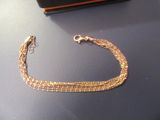 un bracelet en chaîne d'or posé sur une table, à côté d'un portefeuille