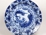 une assiette bleue et blanche ornée d'un oiseau, posée sur un socle