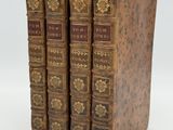 three old books sitting on top of each other on a white surface