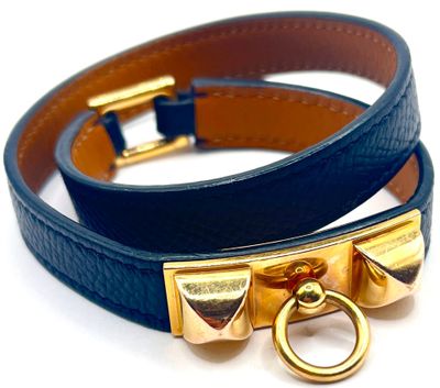deux bracelets en cuir bleu rehaussés de détails en métal doré sur fond blanc
