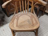 a wooden chair with a woven seat in the middle of a room