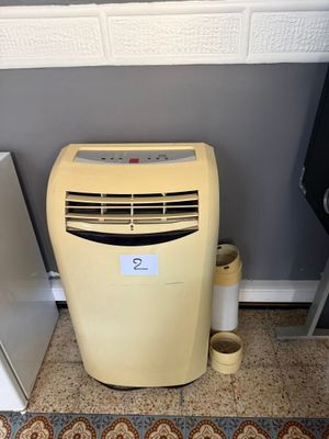 un petit climatiseur posé à côté d'un réfrigérateur