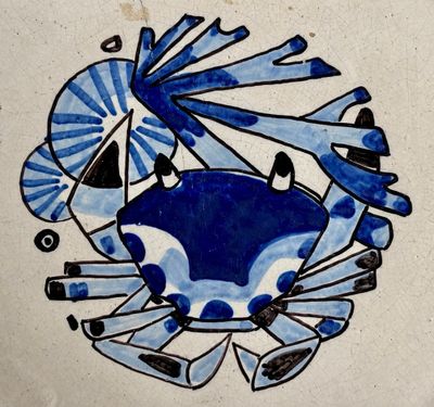 un crabe bleu et blanc sur un carreau orné d'un éventail
