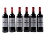 six bottles of wine are lined up in a row on a white surface