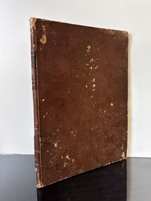 un vieux livre posé sur une table noire, près d'un mur blanc
