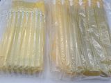 yellow and white plastic straws in plastic bags on a white surface
