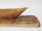 carvings of a boat on a wooden base on a white surface