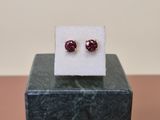 a pair of red earrings sitting on top of a marble block
