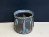 a blue vase sitting on a table with a black background