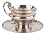 tasse à thé et soucoupe plaquées argent, posées sur une soucoupe, sur fond blanc