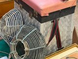 une valise rose posée sur une table à côté d'un ventilateur