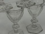 four clear glass goblets sitting on top of a white table