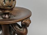 a bronze candle holder with a cup on it