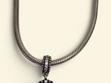 a close up of a silver necklace with a pearl on it