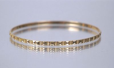 a close up of a gold bracelet on a white surface