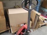 a stack of boxes on the floor next to a hand truck