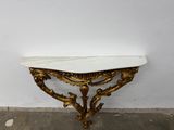 an antique console table with a marble top in a corner