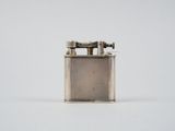 un vieux briquet en argent posé sur une surface blanche