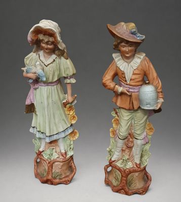 pair of porcelain figurines of children with hats and flowers