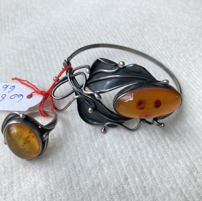 une paire de bracelets argentés et ambrés posés sur une surface blanche, avec une étiquette de prix