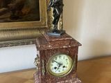 une statue d'un homme tenant une horloge au-dessus d'une table