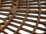 a metal grate with holes on it in the snow