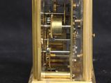 a small gold clock with a cigarette in front of it