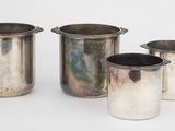 trois vases en argent et une coupe en argent posés sur une surface blanche